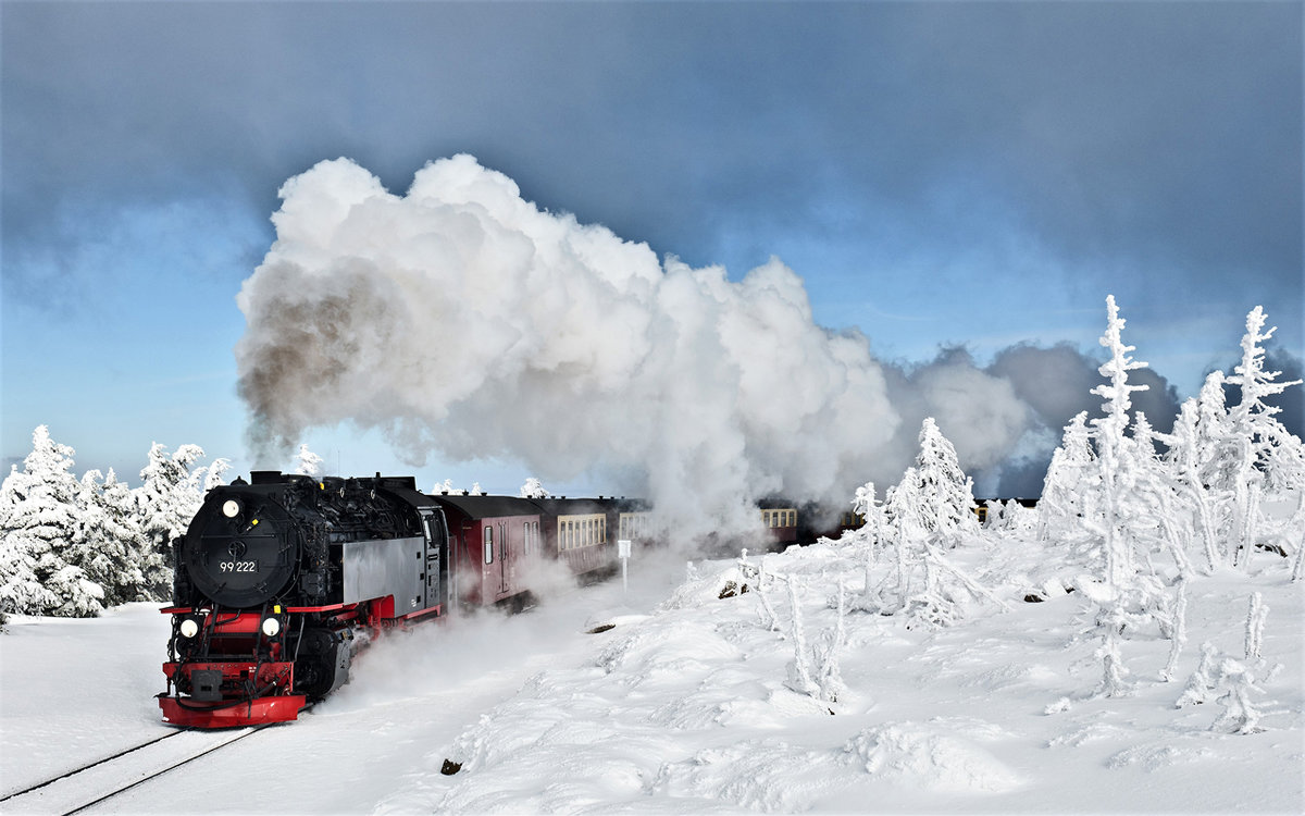 Ein mildes Licht strahlt ganz kurz durch den Nebel hindurch als Die Dampflokomotive 99222 mit dem Brockenzug 8925 vor der Bergstation Brocken Bf den Berg hinaufdampft.Bild 13.2.2018