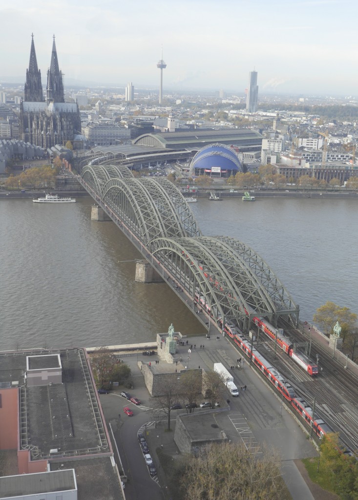 Ein RE 22 aus der Eifel (3-fach 644) und ein RE 1, geschoben von einer 146 am rechtsrheinischen Ende der Kölner Hohenzollernbrücke (9.11.14), aufgenommen von der Aussichtsplattform, leider mit einem leichten Reflex von der Schutzverglasung.