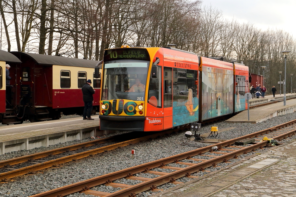 Ein Siemens Combino Duo-Hybridtriebzug der Nordhäuser Straßenbahn mit Fahrziel Neanderklinik am Nachmittag des 25.02.2017 beim Verlassen des Bahnhofes Ilfeld. Für diesen ist der hinten stehende IG HSB-Sonder-PmG kurz zuvor auf Gleis 2 rangiert.