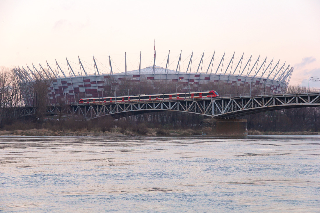 Ein SKM-Triebzug vor der Kulisse des Nationalstadions in Warschau, das sich neben der Weichsel befindet.
Aufgenommen am 7. Dezember 2015.