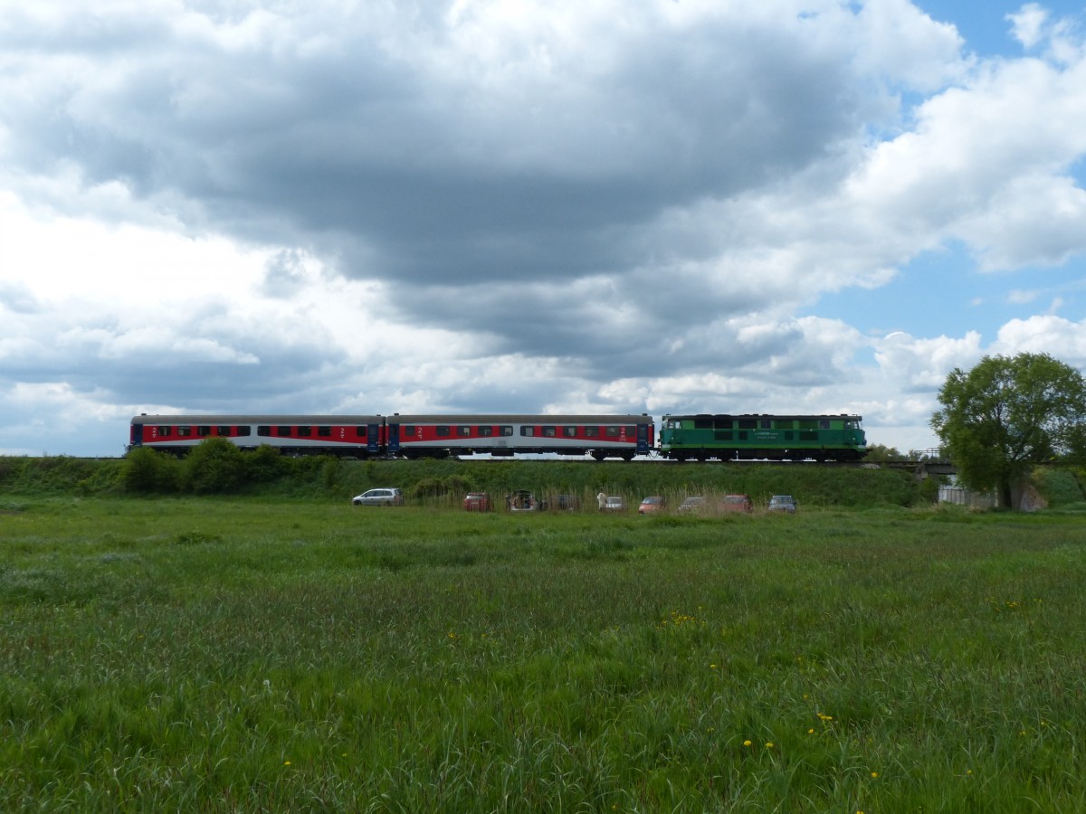 Ein Sonderzug mit modernen Regionalzugwagen aus Poznan kommt in Wolsztyn an. Davor stehen bereits die Autos der Eisenbahnfans, welche den nach wie vor nicht so überlaufenen südöstlichen Streckenteil aufsuchen und dort auf gute Fotos hoffen. 3.5.2014