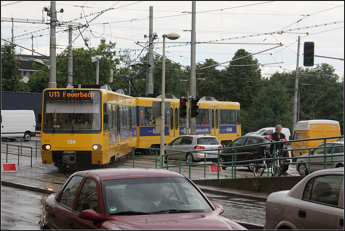Ein sperriger Doppeltriebwagen -

... sucht sich seinen Weg zwischen zahlreichen Masten, Geländer und Autos. Es scheint fast so als wäre der Bogen hier zu eng. Die Stuttgarter Stadtbahnwagen haben einen Mindestradius von 50 Meter, was im Straßenbahnbereich sehr hoch ist. Die Stadtbahnwagen B in NRW kommen mit 25 Meter aus. In Stuttgart führte es dazu, dass das Gleisnetz für die Stadtbahn sehr großzügig ausgebaut werden musste.

Im Bild befährt ein über die Wilhelma umgeleiteter Zug der Linie U13 über die Verbindungskurve an er Haltestelle Rosensteinbrücke. Im Regelbetrieb kommt die Linie von links, wo im Bild das Gleis durch die rote Tafel abgesperrt ist.

Die Situation wird sich hier in einigen Jahren verändern, die Autos werden zu einem Großteil im Rosensteintunnel verschwinden und die Straßen hier können zurückgebaut werden.

30.07.2010 (M)