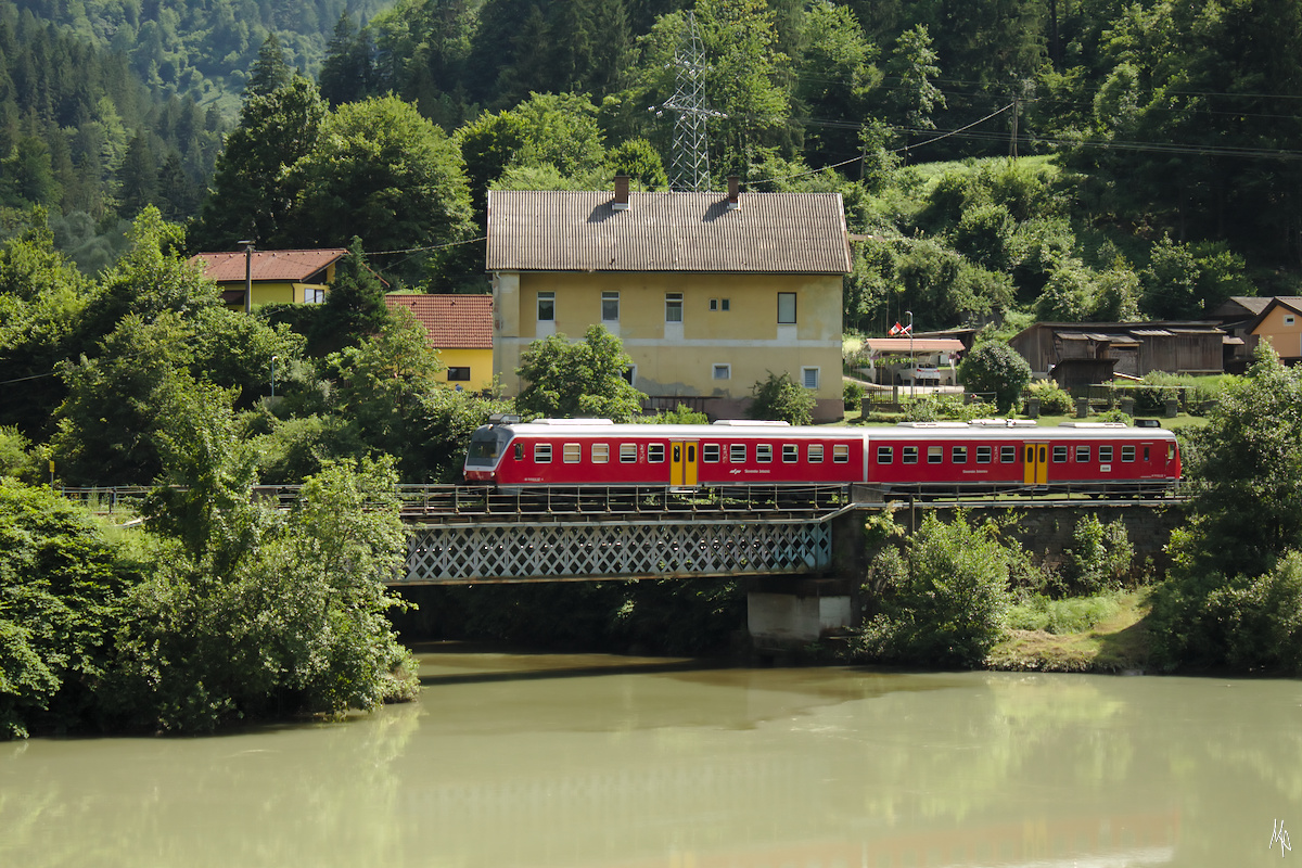 Ein Triebwagen der Baureihe 813 passiert gerade die Brücke über die Velka. In der trüben Drau im Vordergrund bleibt die erhoffte Spiegelung leider aus. (24.09.2019)