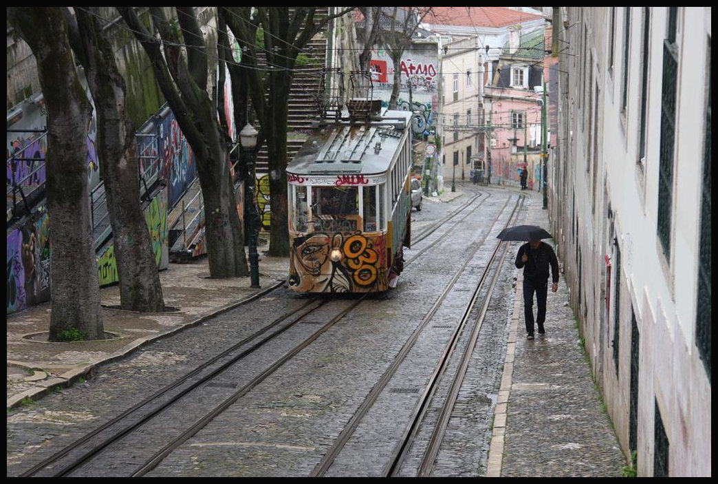 Ein Triebwagen der Standseilbahn in der Taberna da Gloria in Lissabon strebt hier am 19.3.2018 dem Endpunkt der Strecke zu. Im Hintergrund ist noch ein wenig der Gegenwagen zu erkennen, der gerade um eine Hausecke entschwindet.
