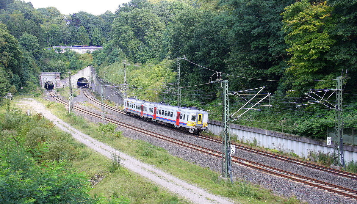 Ein Triebzug der SNCB 646 kommt aus Aachen-Hbf nach Spa-Géronstère(B) und kamm gerade aus dem Aachener-Buschtunnel aus Richtung Aachen-Hbf und fährt in Richtung Hergenrath(B). Aufgenommen von einer Fußgängerbrückein Preusswald bei Aachen.
Bei Sommerwetter am Nachmittag vom 24.8.2017.