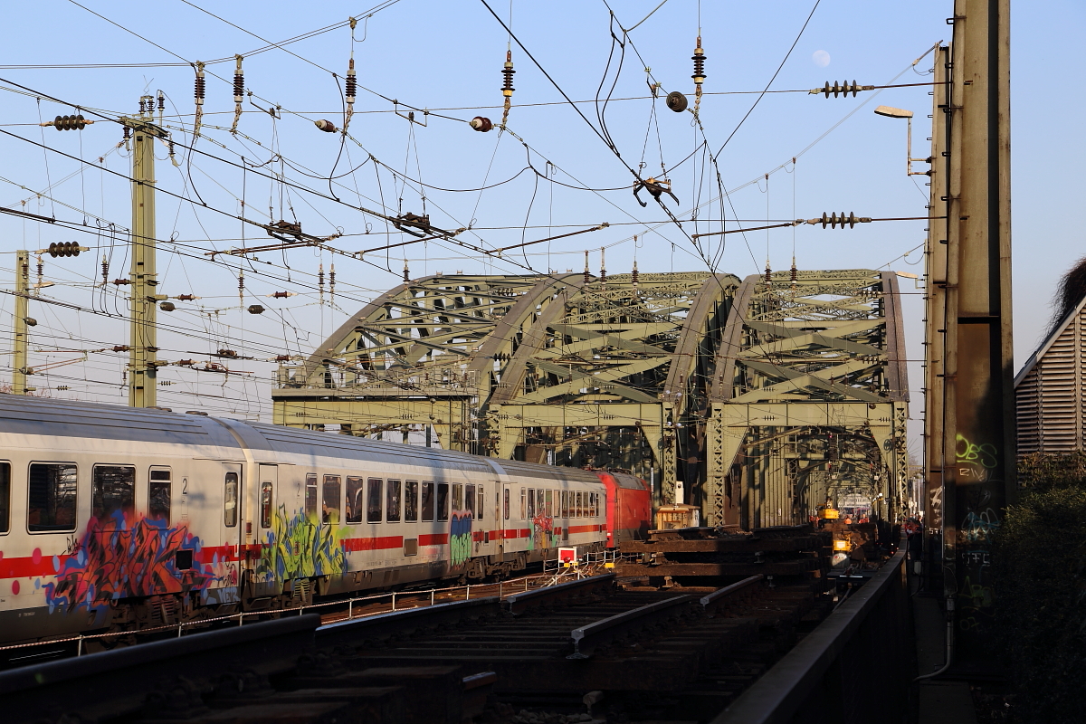 Ein unbekannter InterCity hat am späten Nachmittag des 13.03.2014 soeben den Kölner Hauptbahnhof verlassen und fährt auf die Hohenzollernbrücke. Rechts sind die zurzeit stattfindenden Bauarbeiten, zum Austausch der beiden südlichen Gleise, auf dem Bauwerk zu erkennen, welche noch bis Mitte April andauern und den Zugverkehr erheblich behindern werden.