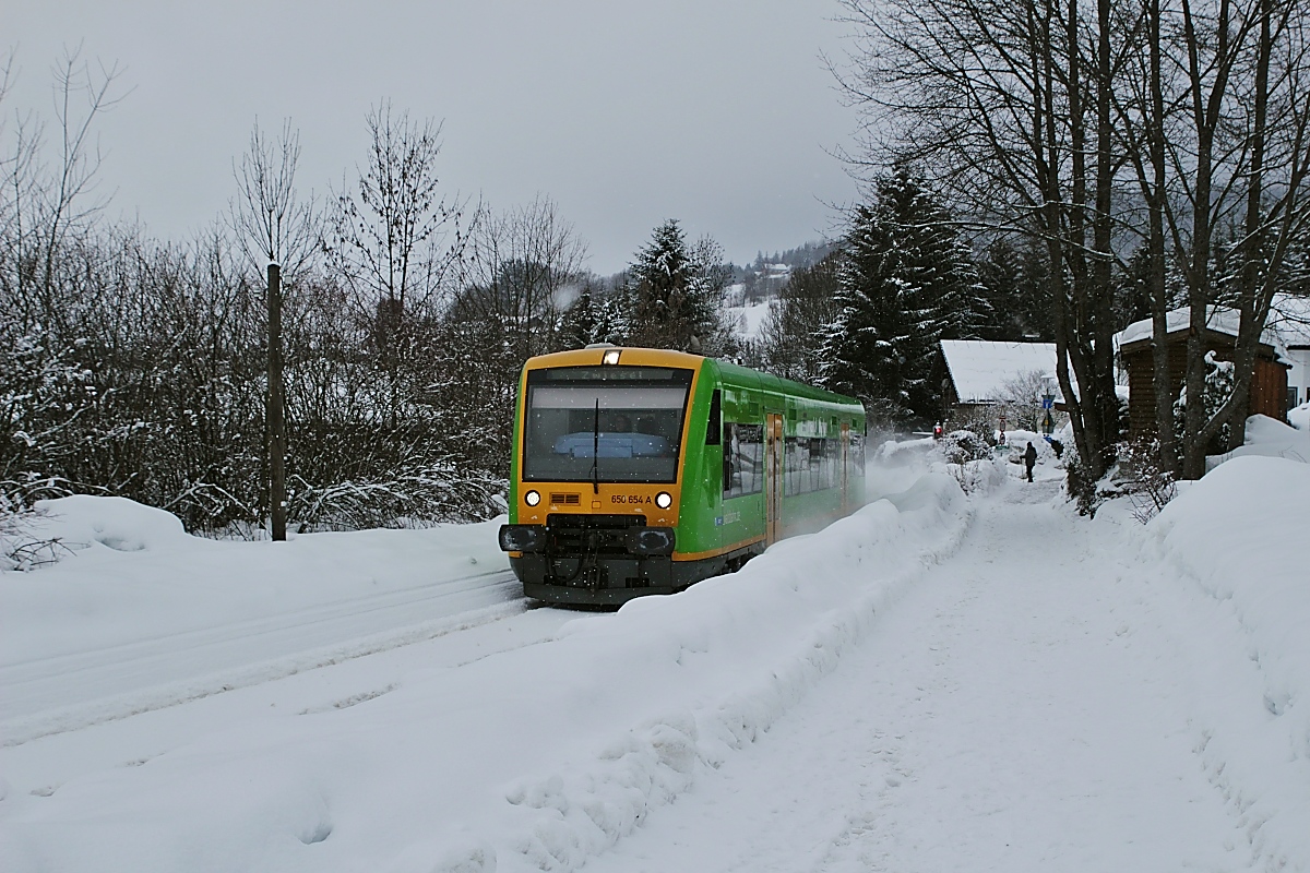 Ein wenig Farbe ins vorherrschende Grau bringt der Waldbahn-650 654, als er am 12.02.2019 Bodenmais verlässt