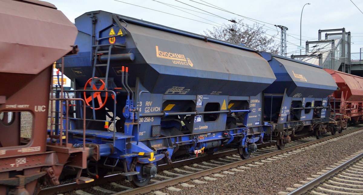 Ein zweiachsiger blauer Schüttgutwagen mit Schwenkdach und dosierbarer Schwerkraftentladung der tschechischen Fa. LOVOCHEMIE a.s. LOVOSICE (Mineraldüngemittelproduzent) mit Firmenlogo mit der Nr. 23 RIV 54 CZ-LVCH 0130 258-5 Tdns in einem Güterzug mit unterschiedlichen Wagentypen für das selbe Ladegut am 31.01.19 Bf. Berlin-Hohenschönhausen.