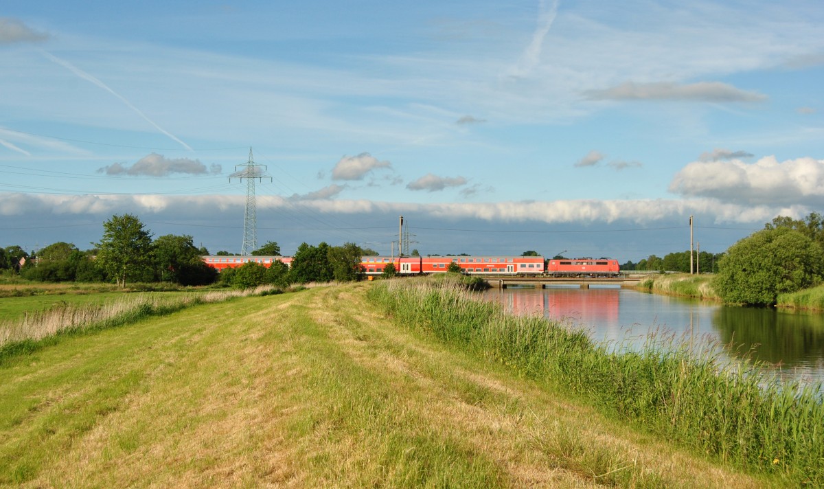 Eine 111 fuhr am 20.06.2015 mit einem RE von Emden nach Münster, hier beim Sauteler Kanal in Neermoor.