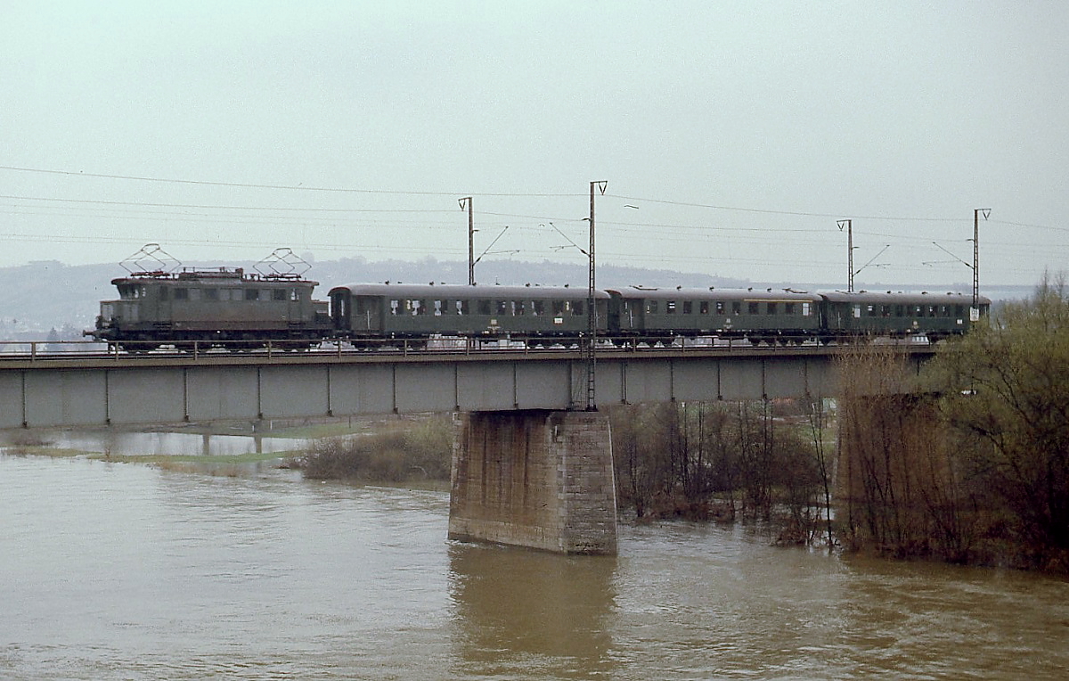 Eine 144 mit einem aus Vorkriegs-Eilzugwagen gebildeten Nahverkehrszug aus Lauda überquert Anfang April 1979 die Mainbrücke in Würzburg