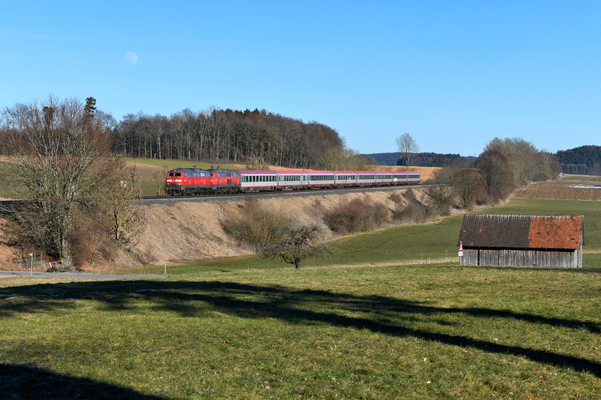 Eine Ära ging dieses Jahr bereits zu Ende: Dieselbespannten Fernverkehr auf der schwäbischen Südbahn wird es nicht mehr geben. Zwischen Ulm und Lindau verkehrt das Zugpaar IC 118 / 119 während der Elektrifizierungsarbeiten nun nicht mehr. Nach Abschluss der Maßnahme soll die Verbindung wieder aufleben, ob dann als ICE oder Railjet steht allerdings noch in den Sternen. An einem der letzten Verkehrstage fuhr ich nochmals nach Oberschwaben, um die Doppeltraktion Ulmer 218er vor den eleganten ÖBB Reisezugwagen zu dokumentieren. Bei Hervetsweiler fuhren mir 218 432 und 438 mit etwa einstündiger Verspätung vor die Linse. Interessantes Detail am Rande: An diesem Tage war der Mond bereits am Nachmittag gut erkennbar (17. Februar 2019).  