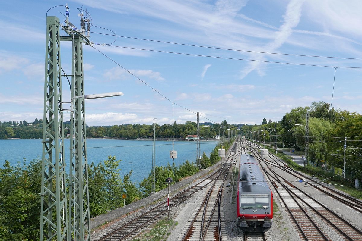 Eine Besonderheit oder normal / üblich? Ein Quertragwerk mit drei Gewichten an den Tragseilen am Beginn des Bodenseedammes in Lindau. Am 11.08.2018 ist RB 22712, Lindau - Friedrichshafen Hafen, kurz nach dem Start unter den herabhängenden Gewichten durchgefahren.