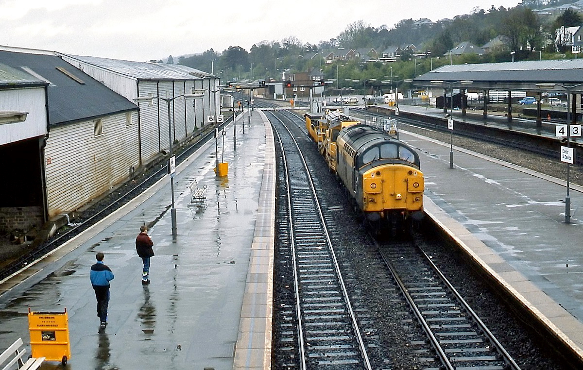 Eine Class 37 der BR durchfährt im April 1992 den Bahnhof Exeter St. Davids. Die jungen Herren links im Bild sind Trainspotter, ihnen geht es nicht ums Fotografieren, sondern sie sammeln Loknummern.