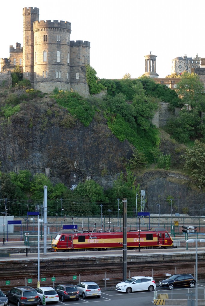 Eine Class 90 (90020) abgestellt im Bahnhof Edinburgh-Waverly als  standby -Lok. Die Lok trägt noch das Farbschema der EWS, gehört jedoch zur DB Schenker Rail (UK) Ltd. Im Hintergrund Governors House auf dem Calton Hill. Der Bahnhof liegt in einem durch Gletscherwanderung enstandenen engen Tal nördlich der Altstadt von Edinburgh, was hier gut sichtbar ist (30.08.2014).
