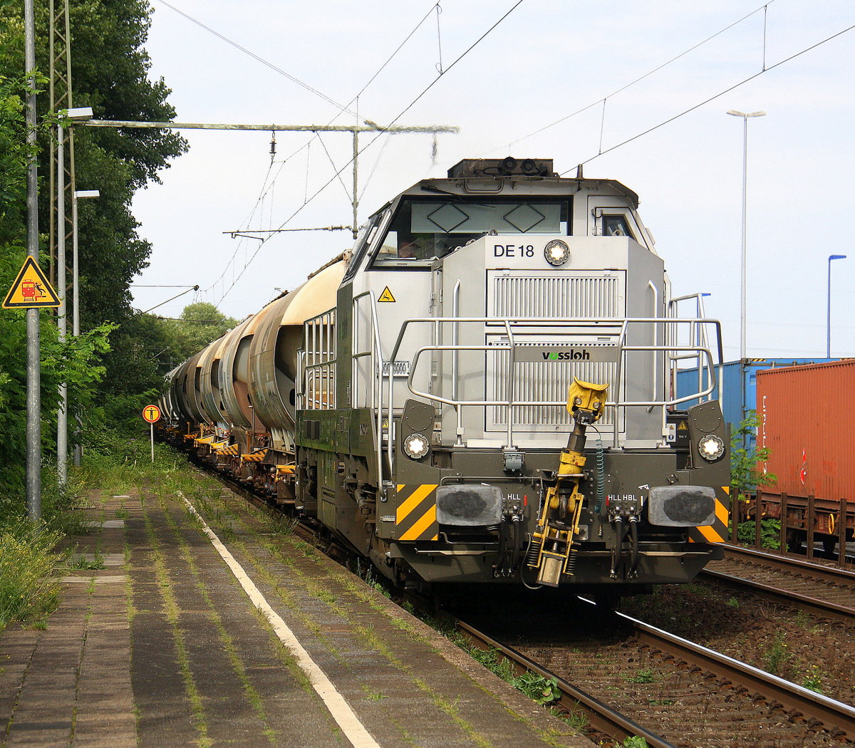 Eine DE18 von Vossloh kommt mit einem Kalkzug aus Rohdenhaus nach Frimmersdorf und kommt aus Richtung Duisburg-Hochfeld-Süd und fährt durch Duisburg-Rheinhausen-Ost in Richtung Duisburg-Rheinhausen,Rheinhausen. 
Aufgenommen vom Bahnsteig in Duisburg-Rheinhausen-Ost. 
Bei Sommerwetter am Nachmittag vom 27.7.2017.