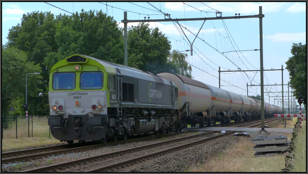 Eine dicke Fotowolke verdeckte gerade die Sonne ,als die Captrain Class 66 mit ihren
Kesselwagenzug am Haken den Bahnübergang unweit von Echt (NL) passiert. Szenario vom 10.Juni 2015 unweit von Roermond in den Niederlanden.