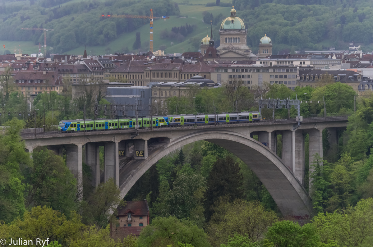 Eine Doppeltraktion aus zwei 4-teiligen NINA befhrt am 2. Mai 2015 den Lorraineviadukt kurz vor dem Bahnhof Bern. Die hintere NINA ist Werbetrger fr die Gurtenbahn, die Standseilbahn auf den Berner Hausberg. Im Hintergrund das Bundeshaus.