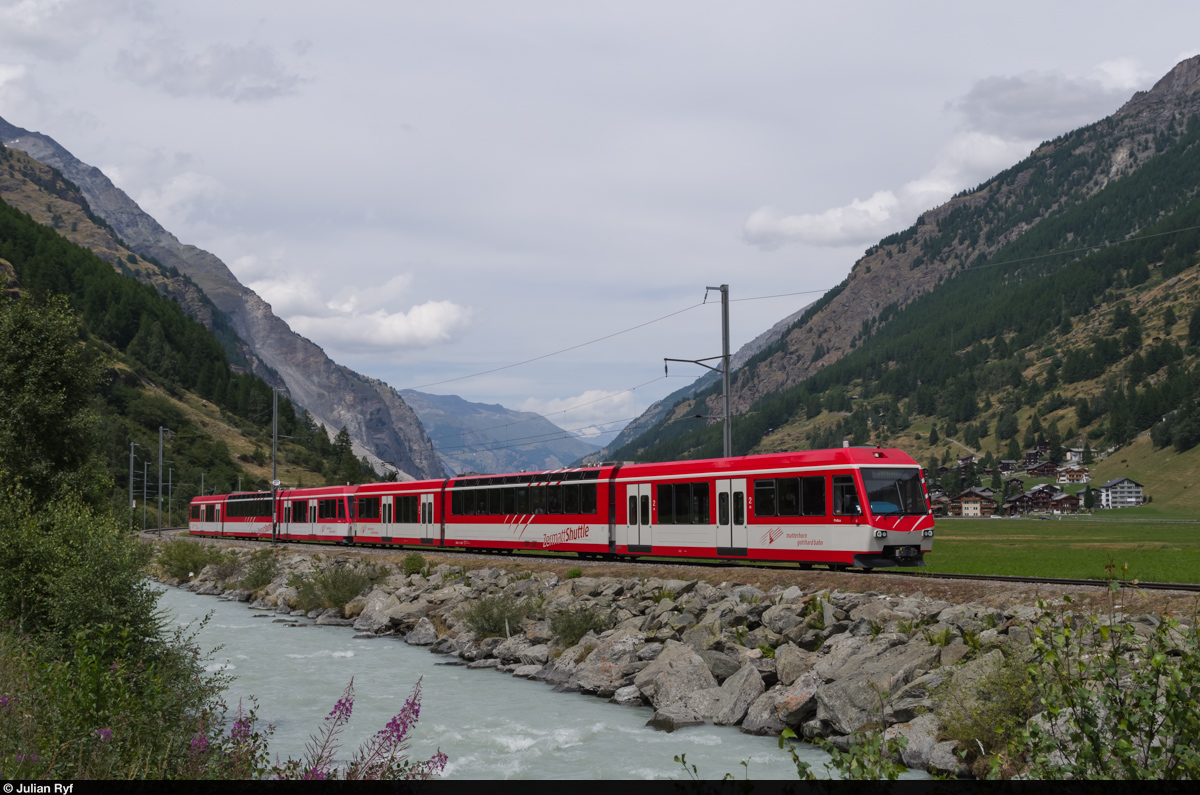 Eine Doppeltraktion BDSeh 4/8 der MGB fährt am 31. Juli 2015 kurz nach Täsch in Richtung Zermatt. Die Shuttlezüge verkehren tagsüber im 20-Minuten-Takt und bringen vor allem mit dem Auto angereiste Gäste vom Matterhorn-Terminal Täsch ins autofreie Zermatt. Zu diesem Zweck verfügen die Züge im Niederflurteil über keine Sitzplätze, sondern bieten stattdessen viel Platz für Gepäcktrolleys.