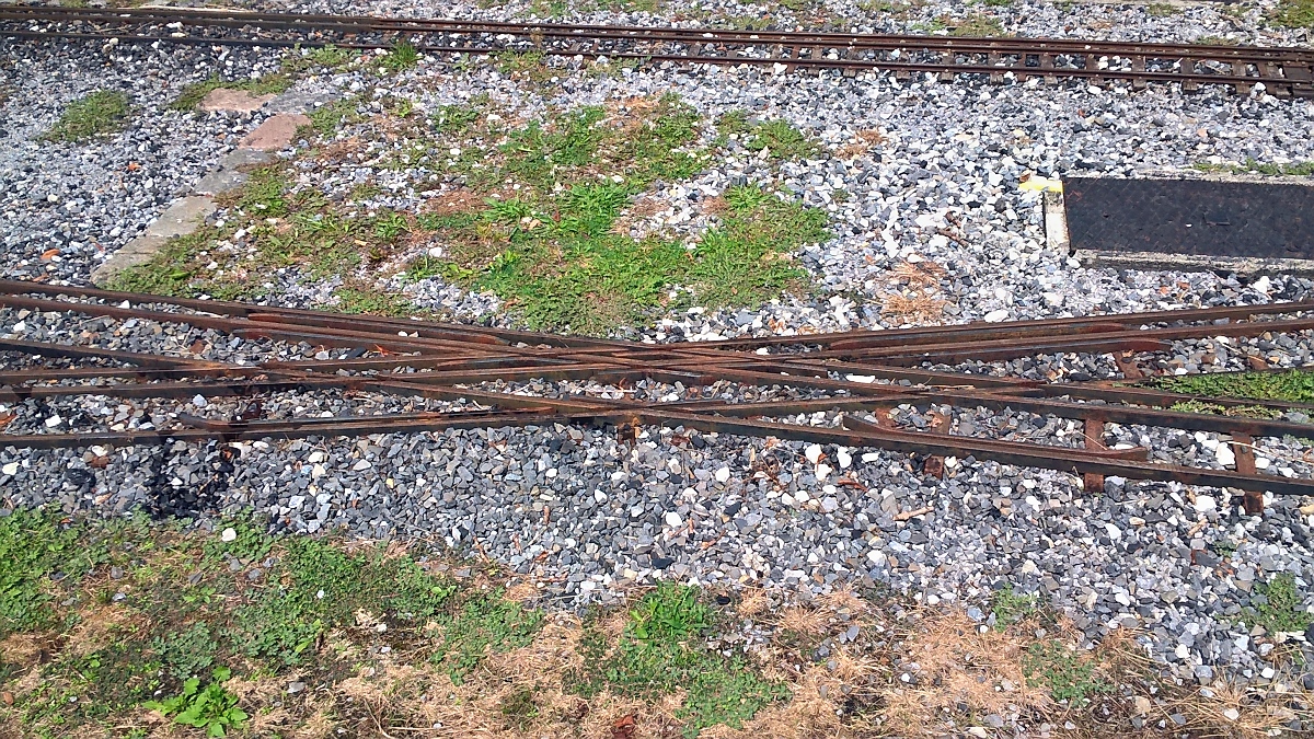 Eine Dreischienengleis-Kreuzung ist ein kompliziertes Gewirr von Gleisen. 
Gartenbahn im Maximilian-Park in Hamm, 21.7.2018
