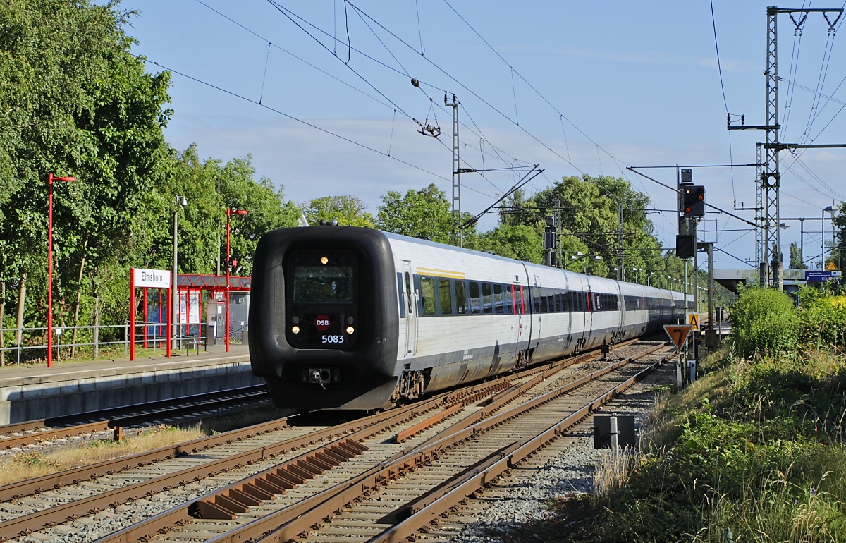 Eine IC3-Dreifachtraktion, vorne MFA 5083, ist mit dem IC 1182 am 10.07.2023 von Hamburg nach Aarhus unterwegs, hier bei der Durchfahrt in Elmshorn. Das Foto entstand vom Zugang zum Bahnsteig aus.