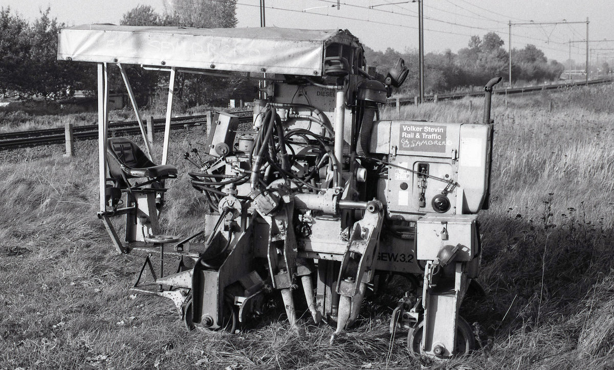 Eine kleine Stopfmaschine der Gleisbaufirma Volker Stevin.
Gebaut von Plasser & Theurer, Fnr.2794, Baujahr 1992, Typ PKS.
Babberich, Kwartiersedijk, 23.10.2000.
Ilford FP4Plus Neg.scan.