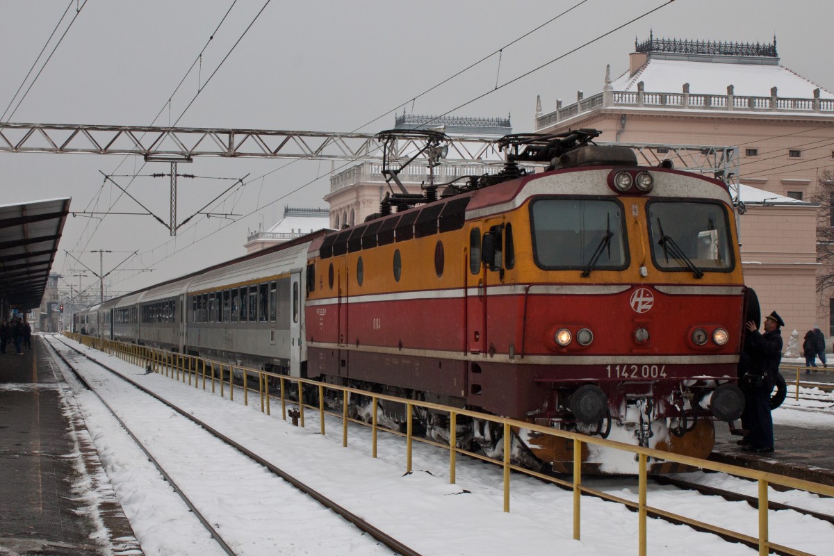 Eine kurze Pause für den EN/D/B 415 (Zürich HB > Beograd) in Zagreb Gl. Kol. 
Hier verliert der Zug Schlaf- und Liegewagen aus Zürich und bekommt stattdessen einige Sitzwagen für den kroatischen Binnenverkehr bis Vinkovci zugestellt. 
Gemeinsam mit einem serbischen Grossraumwagen 2. Klasse, der als Einziger Wagen aus Zürich die gesamte Strecke durchläuft, und je einem 1. und 2. Klassewagen der selben Serie aus Villach geht die Reise nach planmässig rund einer halben Stunde Aufenthalt weiter in Richtung Belgrad. 
Der eigentlich für diesen Zug ebenfalls geplante Speisewagen war an diesem Tag leider nicht dabei, sodass ich die Zeit in Zagreb nutzte, mir Verpflegung für die verbleibenden gut sechs Stunden Fahrt zu besorgen. 
Gezogen wurde der Zug auf dem kroatischen Abschnitt von der 1142 004, die den grauen Tag herrlich kontrastierte.
29. Januar 2014