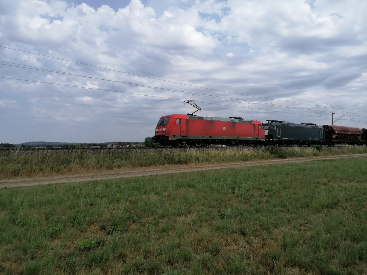 Eine Lok der Baureihe 185 375-3 der DB zieht einen Güterzug aus Schüttgutwagen und einer kalten Lok 185 553-5 der MRCE Dispolok Richtung Ansbach. Auffällig ist wie gut der Zustand der Dispolok im Vergleich zur DB-Lok ist. Aufgenommen an der Bahnstrecke Treuchtlingen-Würzburg in der Nähe von Triesdorf am 23.07.2022