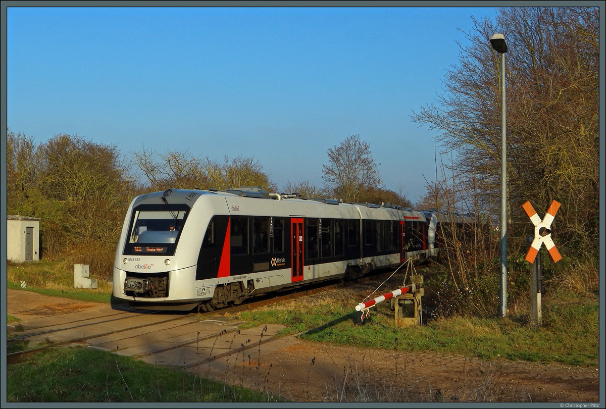 Eine mechanische Halbschranke mit Blinklicht sichert den Feldweg bei Bottmersdorf, damit 1648 952 seine Fahrt Richtung Halberstadt fortsetzen kann. (08.12.2020)
