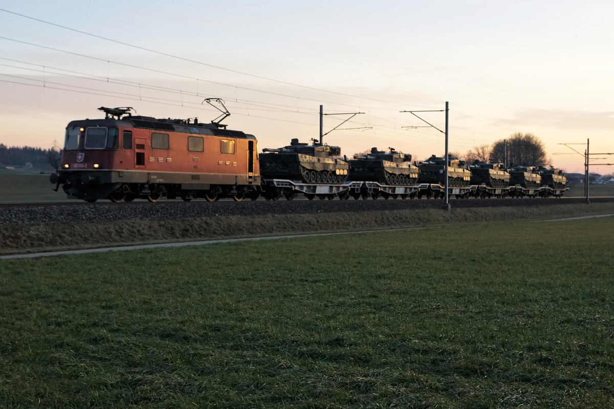 Eine nicht erkennbare Re 420 mit dem Panzerzug 69059 Rangierbahnhof Biel - RBL bei Niederbipp am 26. Februar 2019. Transportiert wurden 6 Panzer Leopard.
Die Aufnahme entstand im allerletzten Sonnenlicht bei einer Verspätung von mehr als einer Stunde.  
Foto: Walter Ruetsch