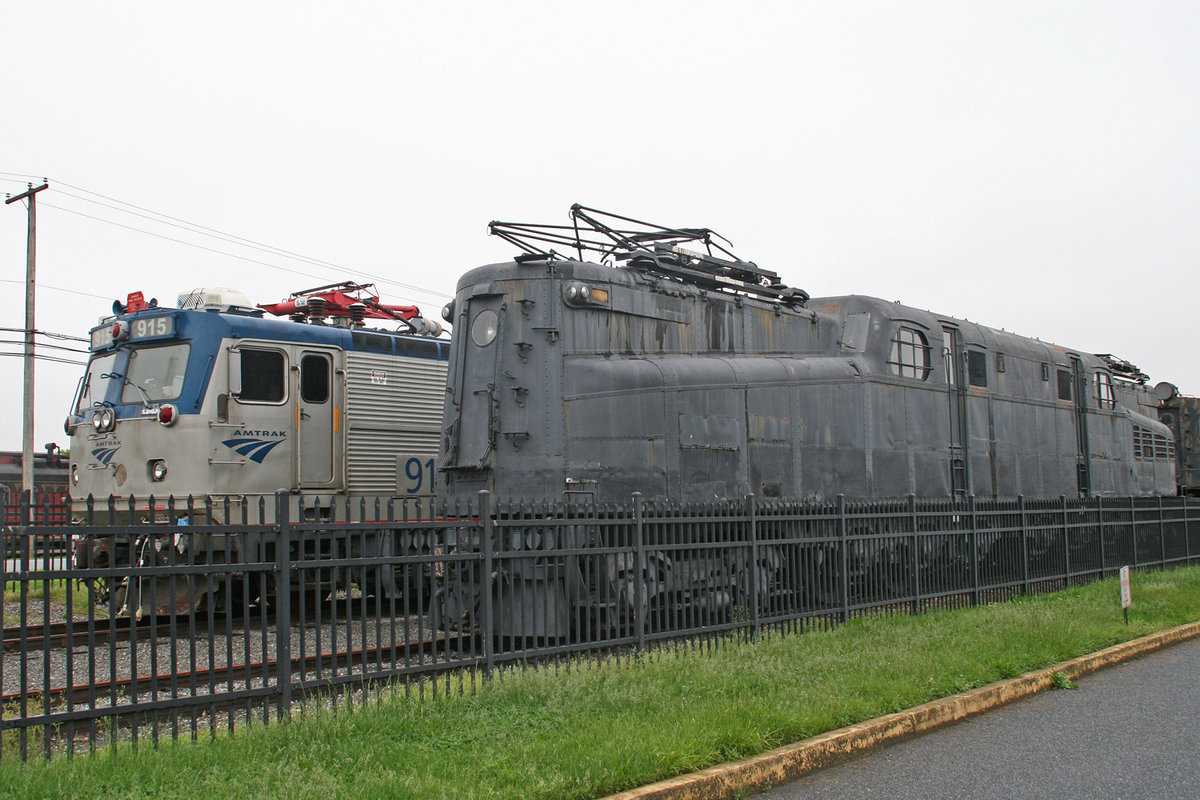 Eine nicht markierte GG-1 der Pennsylvania Railroad steht neben der EMD AEM-7 Nr. 915 der Amtrak auf dem Freigelände des Railroad Museum of Pennsylvania in Strasburg, Pennsylvania / USA, 17. Mai 2018.