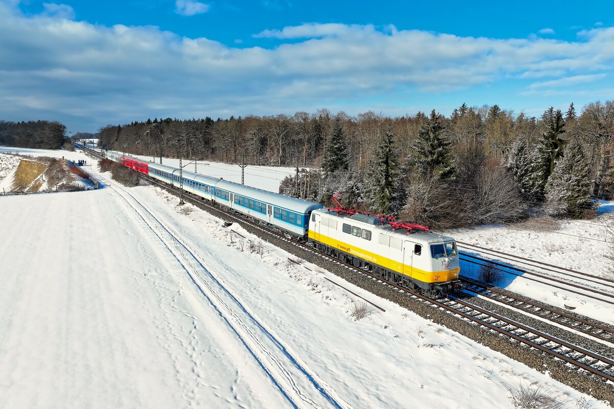 Eine originelle Sonderfahrt fand am 11. Januar 2026 statt. Ein DZ 13400 verkehrte von M�nchen Ost nach Kufstein und bef�rderte Krimi-Fans zum sogenannten H�ttenkrimi. Hierbei wurde ein fiktiver Kriminalfall auf der Feste Kufstein gel�st, inklusive kulinarischer Begleitung. F�r die Fahrt nach Tirol kamen Fahrzeuge der Gesellschaft f�r Fahrzeugtechnik aus Crailsheim - kurz GfF - zum Einsatz. Die inzwischen in den Farben des ehemaligen Lufthansa-Express gehaltene 111 049 verkehrte somit auf einer ihrer fr�heren Stammstrecken, war sie doch lange Zeit in M�nchen beheimatet. Urspr�nglich hatte ich eine Aufnahme des Zuges im Inntal angedacht. Sich rasch verschlechterndes Wetter und eine aufgrund Glatteis-Unf�llen gesperrte Autobahn lie�en mich jedoch auf den Nahbereich von M�nchen umschwenken. Bei Kirchseeon ging sich noch ein Sonnenbild des in den Farben der 1990er Jahre gehaltenen Sonderzuges aus.   