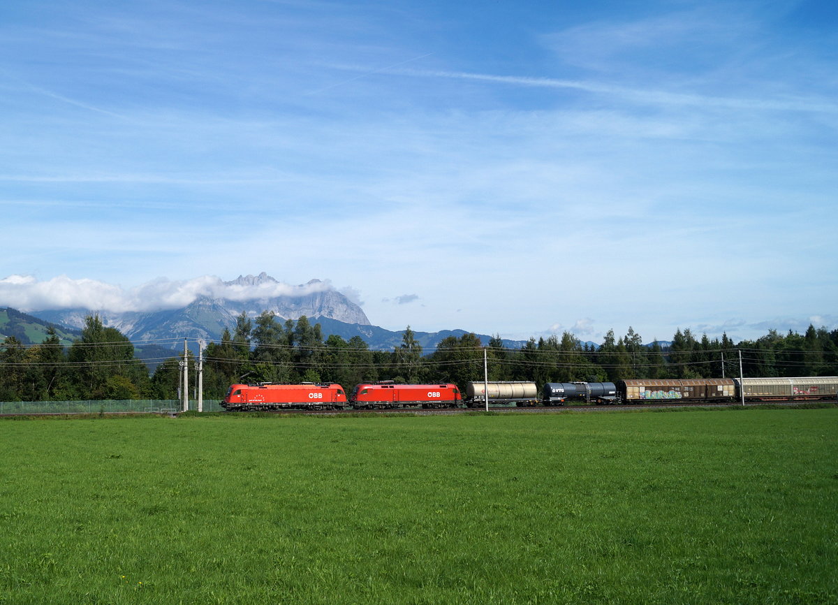 Eine  part of the best -1216 und eine 1016/1116 bringen am 14. September 2019 einen gemischten Güterzug in Richtung Wörgl. Aufgenommen vor der Kulisse des Wilden Kaisers bei Kitzbühel Schwarzsee.