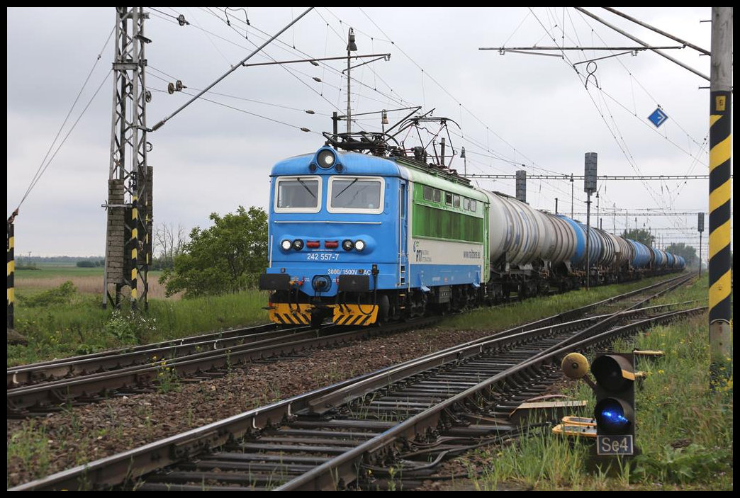 Eine private Altbau Elektrolok mit der Nummer 242557-7 durchfährt hier am 12.5.2019 mit einem Kesselwagen Zug den Bahnhof Tvrdosovce in Richtung Nove Zamky.