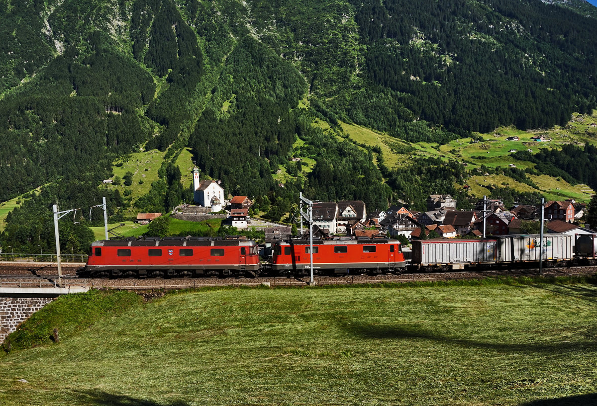 Eine Re 10/10, bestehend aus den Lokomotiven Re 6/6 11678  Bassersdorf  und Re 4/4 II 11322, fährt mit einem KLV, oberhalb von Wassen, in Richtung Gotthard.
Aufgenommen am 19.7.2016.
