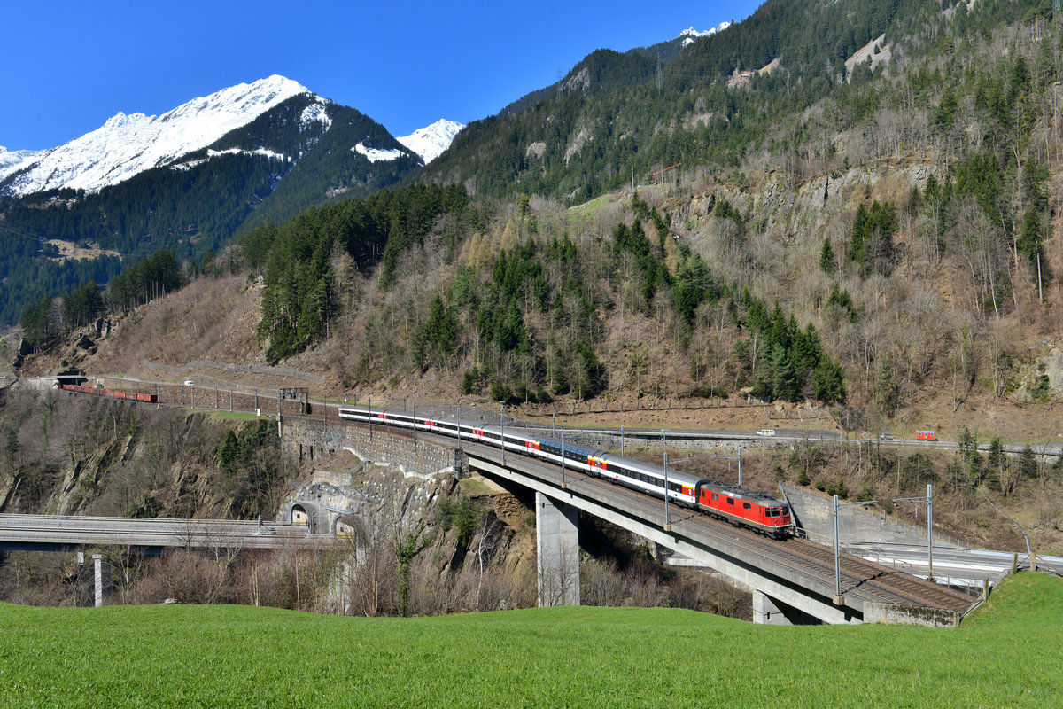 Eine Re 4/4 mit einem IR am 09.04.2015 bei Amsteg. 