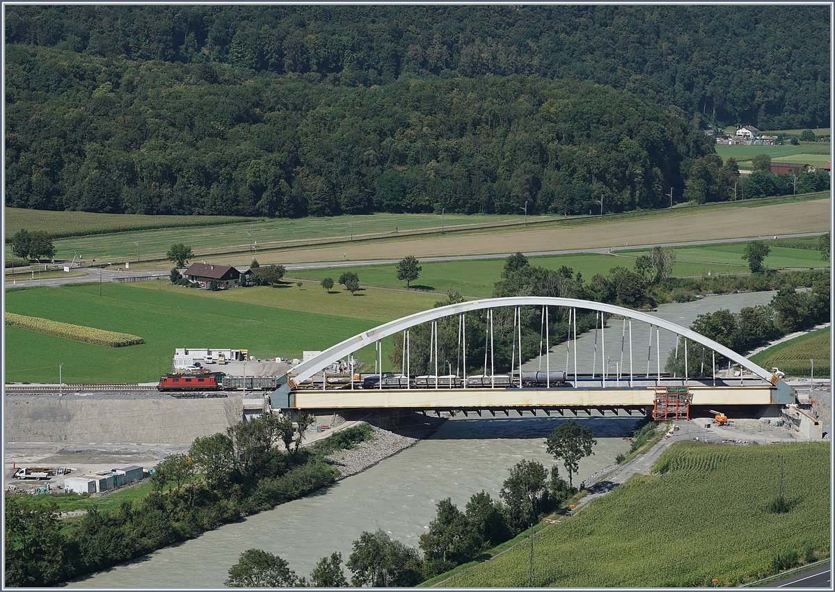 Eine SBB Re 4/4 II mit einem kurzen Güterzug verlässt die Rohnebrücke zwischen Bex und St-Maurice.
Rechts im Bild ist sehr gut ein Teil des nun nicht mehr benötigten Brückenkopfes zu sehen auf welche die Brücke konstruiert und dann verschoben wurde. Doch noch ist die große Brücke nicht an ihrem definitiven Platz.    
26. August 2016