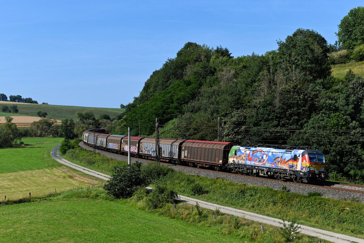 Eine der schönsten aktuell im Einsatz stehenden Werbeloks ist für mich die 193 640 von MRCE. Der Vectron ist an TXLogistik vermietet und weist mit seiner farbenfrohen Gestaltung auf seinen primären Einsatz auf der Brennerachse zwischen München und Verona hin. Landesflaggen und Sehenswürdigkeiten wurden gekonnt in das Design mit einbezogen. Mit der  Deutschen Seite  voraus konnte ich die Maschine am 18. Juli 2020 bei Hermannspiegel im Haunetal fotografiren. Interessant war die Zugleistung: Es handelte sich hierbei um den aus H-Wagen gebildeten DGS 46706 von Pordenone nach Rostock Seehafen, der normalerweise über den Frankenwald verkehrt. 