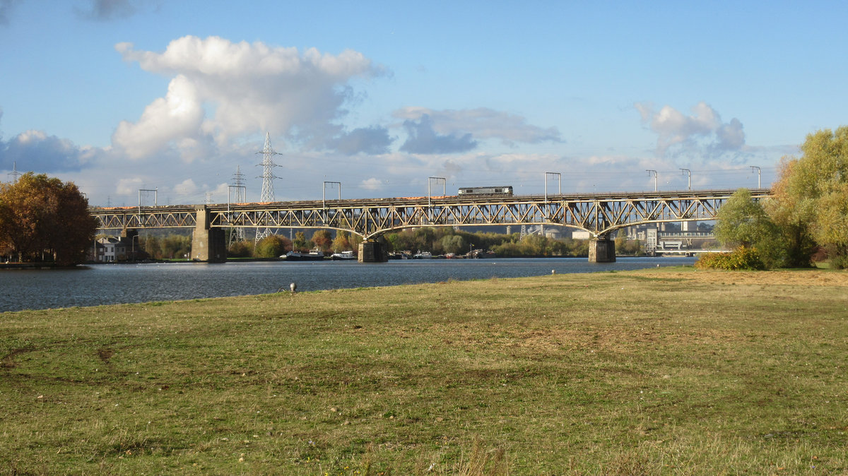 Eine schwarze Class 66, ich vermute die 266 118 von Railtraxx, zieht ihren Güterzeug fast im Schritttempo über die Maasbrücke in Visé gen Aachen-West. Die Aufnahme entstand am 05/11/2016.
