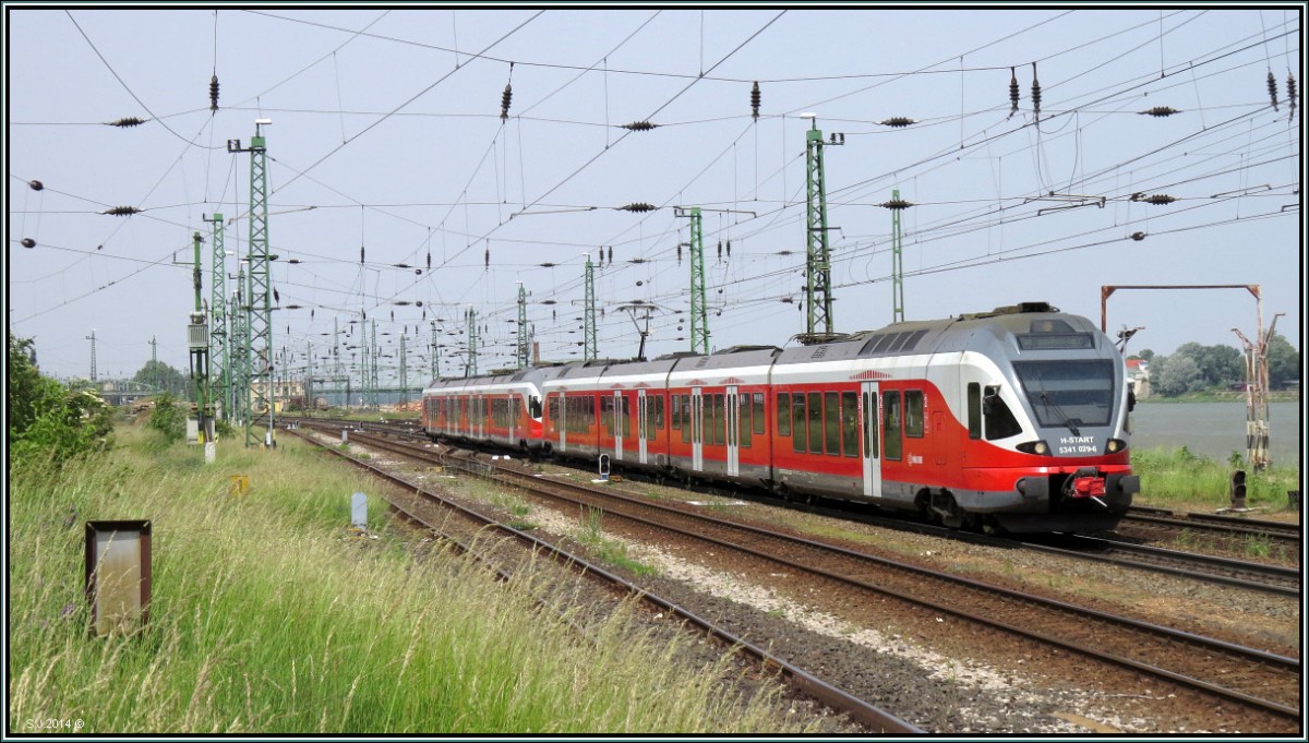 Eine Stadler Flirt Garnitur ist nach Budapest Deli unterwegs am Vormittag des 23.Mai 2014. Bildlich festgehalten am Donauufer bei Komarom.