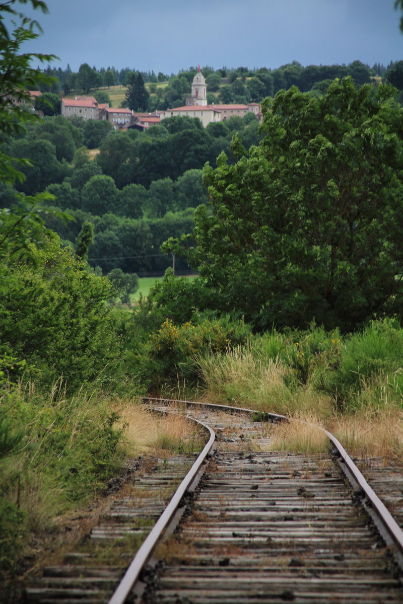 Eine Strecke wie im Dornröschenschlaf:  La ligne du Puy à Langogne  verband einst Le Puy-en-Velay mit Langogne. In Langogne bestand dann Anschluss an die Cevennenbahn (Clermont-Ferrand - Nimes). Doch Züge fahren hier schon lange nicht mehr. Nur gelegentlich rollen ein paar Draisinen über diese Strecke. Gleich ist aus Richtung Langogne der Bahnhof von Pradelles erreicht. Der Ort liegt etwas oberhalb des Bahnhofs.
Pradelles, 13. Juli 2016