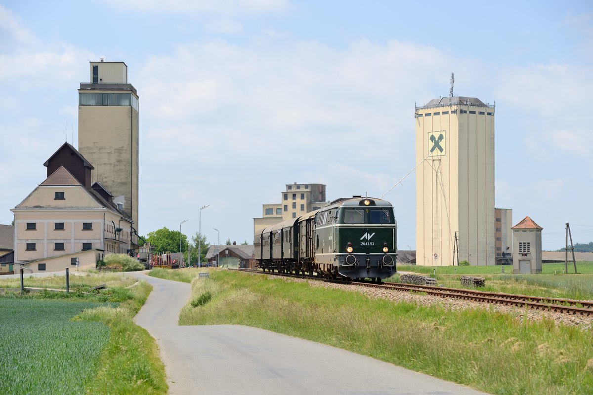 Eine surreale Atmosphäre ergab sich in Weitersfeld. Hier wurde am 04. Juni 2015 der Reblaus-Express bei seiner Rückfahrt nach Retz bei flirrender Mittagshitze unter der Kulisse von drei imposanten Lagerhäusern aufgenommen, die gleichsam aus dem Nichts kommend einsam auf weiter Flur stehen. Wir befinden uns hier an der Grenze vom Wald- zum Weinviertel.