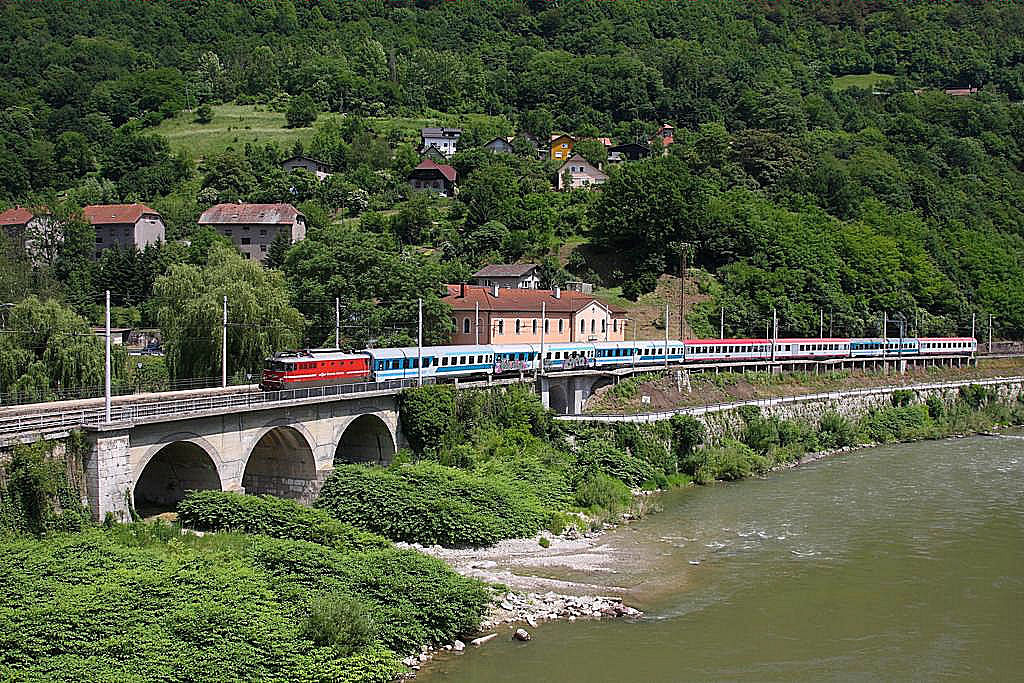 Eine SZ Altbau Elektrolok der Reihe 342 fährt am 29.5.2011 mit einem Schnellzug bergauf entlang der Sava durch den Bahnhof Hrastnik.