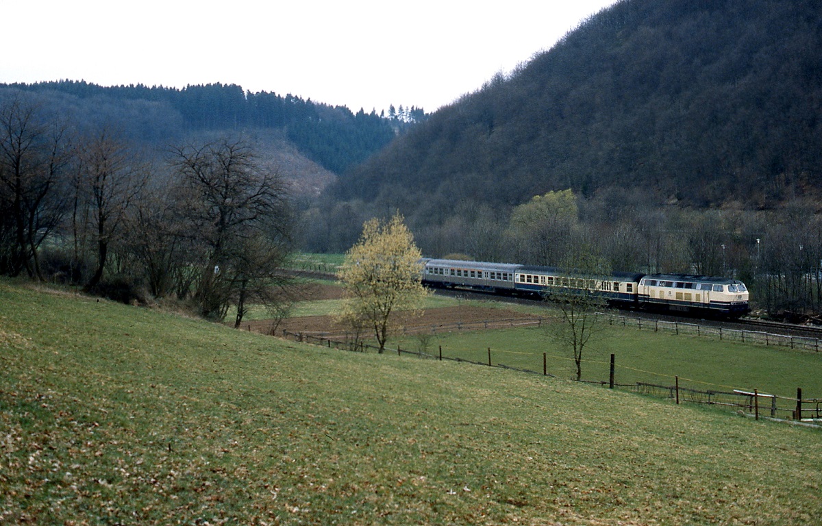 Eine unbekannte 215 hat an einem Frühjahrstag Ende der 1980er Jahre auf ihrem Weg von Köln nach Trier gleich den Haltepunkt Urft erreicht