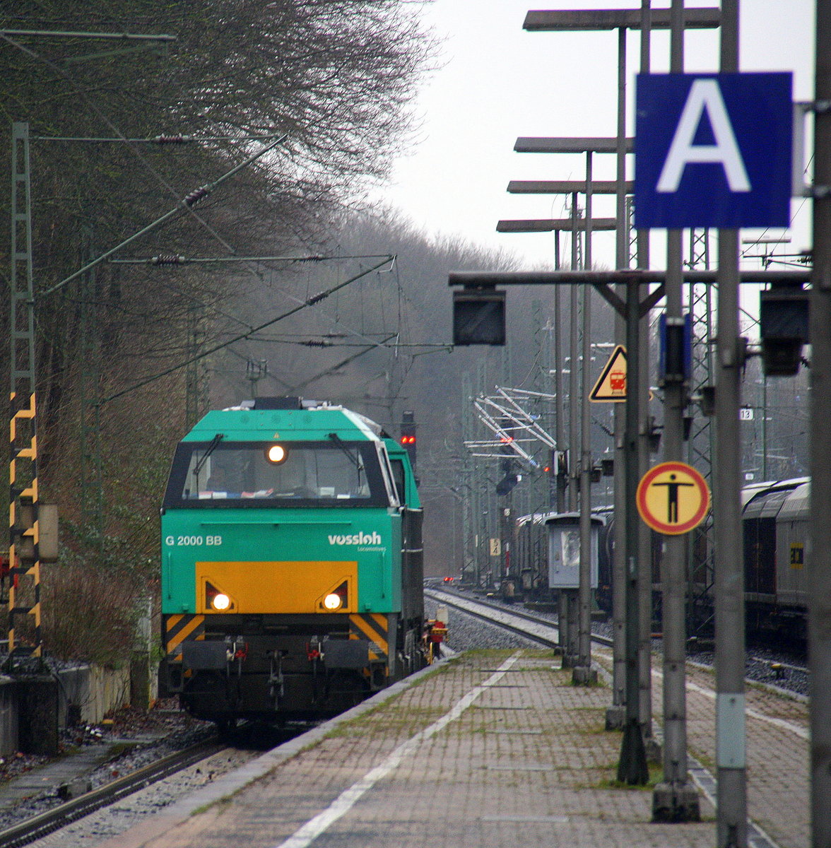 Eine Vossloh Dieselok G 2000 BB von LOCON kommt mit einem Containerwagen aus Richtung Rheydt,Wickrath,Beckrath,Herrath,Erkelenz,Baal,Hückelhoven-Baal,Brachelen,Lindern,Süggerrath,Geilenkirchen,Frelenberg,Zweibrüggen,Übach-Palenberg,Rimburg,Finkenrath,Hofstadt,Herzogenrath, Kohlscheid,Richterich,Laurensberg und fährt durch Aachen-West in Richtung Aachen-Schanz,Aachen-Hbf.
Aufgenommen vom Bahnsteig in Aachen-West. 
Bei Regenwetter am Nasskalten Nachmittag vom 31.3.2016. 