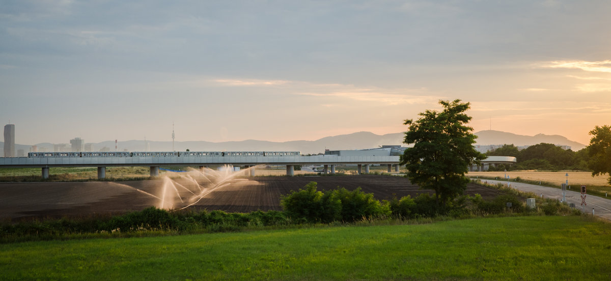 Eine Wiener U-Bahngarnitur der Type U11 unterwegs zwischen  Aspern Nord  und  Seestadt , am Weg Richtung Seestadt.

Im Zuge des Stadterweiterungsgebietes  Seestadt  sollen die Ackerflächen im Endausbau auch entwickelt werden.
Im Vordergrund die AB zu  Opel/General Motors 

Im Hintergrund ist die Wiener  Skyline  mit dem DC-Tower und dem Donauturm zu sehen.
