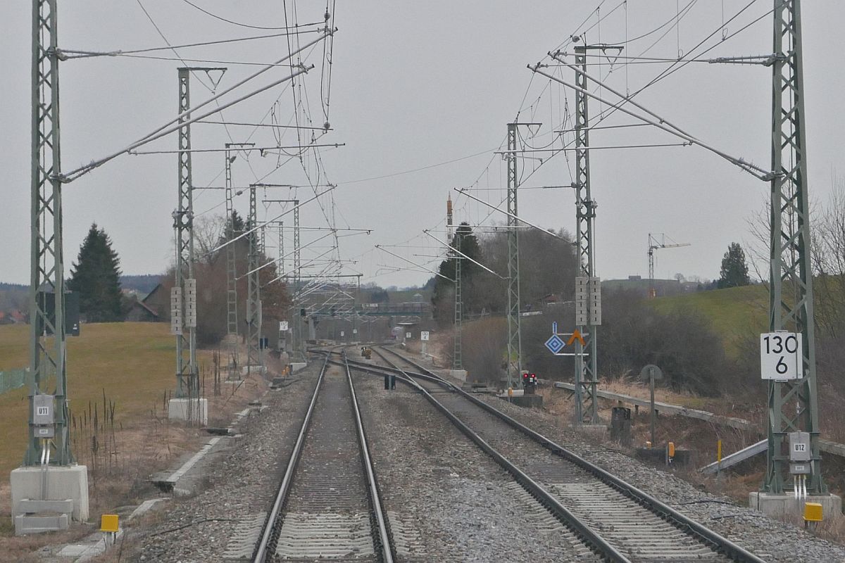 Eineinhalb Wochen vor dieser Aufnahme war an der rechts hinten zu sehenden Weiche unten ein kleines Fahrleitungssignal mit Richtungspfeil angebracht. Am 03.03.2021 hat ein großes Fahrleitungssignal mit Richtungspfeil auf mittlere Höhe vor dem Spurwechsel von der bayerischen auf die württembergische Allgäubahn das bisherige Signal ersetzt. Möglicherweise ist das größere und weiter vorne angebrachte Signal auf die Panne bei der mißglückten Premierenfahrt eines Astoro von Zürich Richtung München am 13.12.2020 zurückzuführen. Foto wurde durch die geschlossene Tür zwischen Fahrgastraum und Führerstand eines Triebwagens der Baureihe 650 gemacht, der sich als RB 92 auf der Fahrt von Aulendorf nach Lindau-Insel kurz nach Hergatz befand.