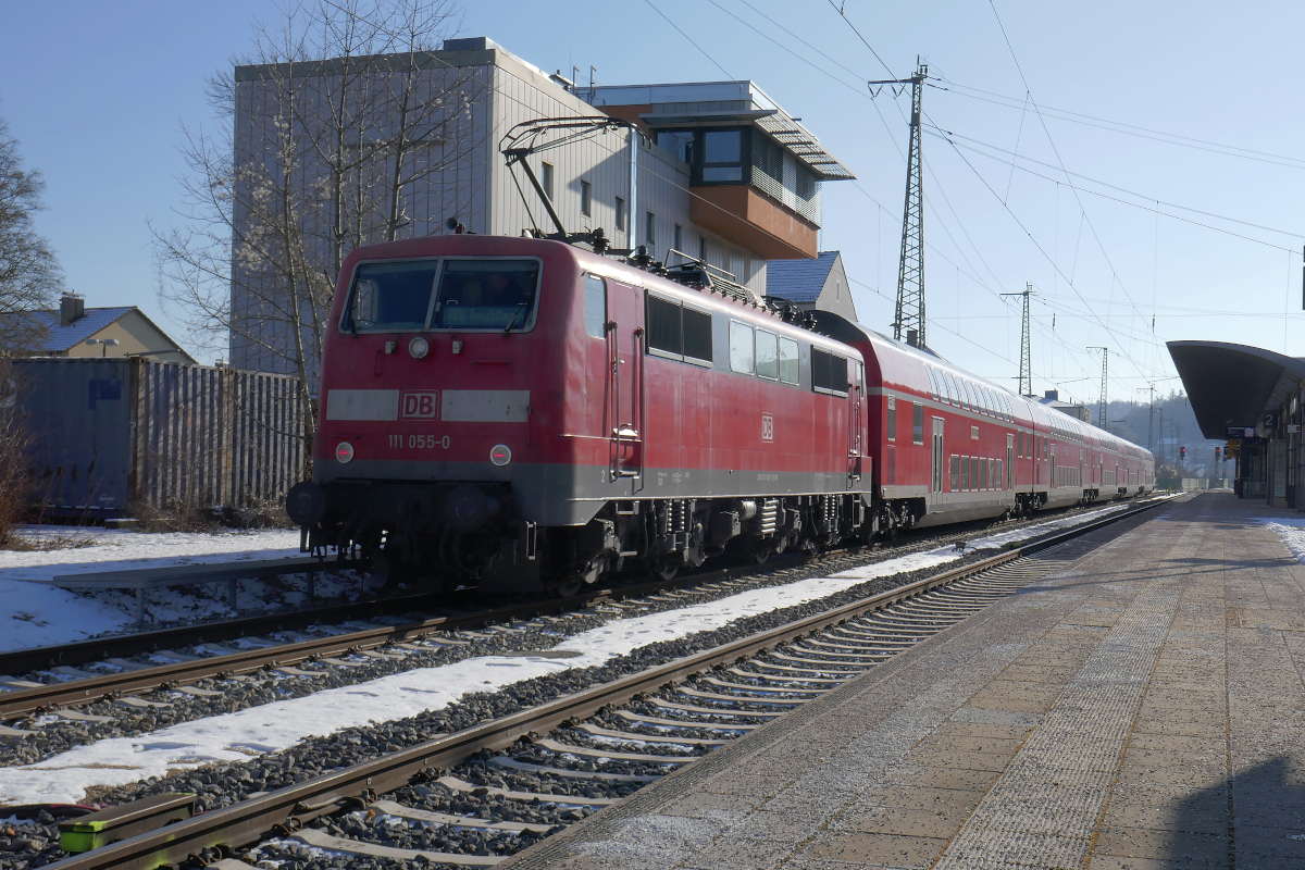 Einer der Züge, welcher als RB16 zwischen München und Treuchtlingen pendelt, ist mit einer Lok 111 bespannt. Am 8. Februar 2023 steht 111 055 zur Fahrt nach München in Treuchtlingen auf Gleis 1 bereit.