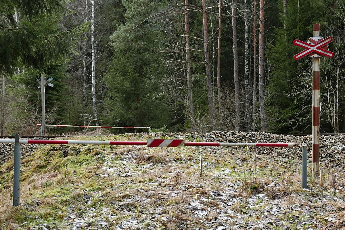 Einfache und zierliche Schranken an einem Bahnübergang für einen Waldweg zwischen Černý Kříž und Stožec, der Bahnstrecke Číčenice - Nové Údolí, Streckennummer 197 (31.12.2019).