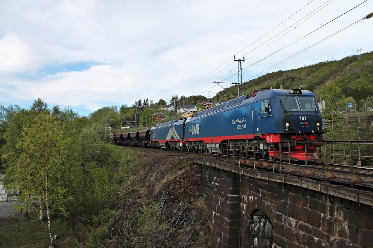 Einfahrt am 01.06.2015 von LKAB IORE 107  SVAPPAVAARA  und LKAB IORE 112  VASSIJAURE  mit einem vollen 8600t schweren in den Bahnhof von Narvik, als sie am Friedhof von Narvik vorbei fuhren.