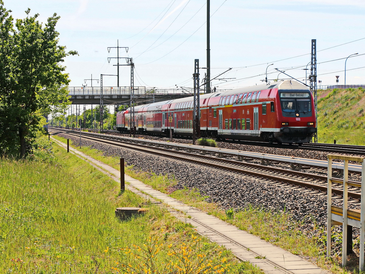 Einfahrt RE 7 nach Bad Belzig kurz vor dem Bahnhof Berlin Flughafen Schönefeld am 21. Mai 2020 mit Schublok 112 155-7 und Doppelstock Steuerwagen. Standort an der Waßmannsdorfer Chaussee (B 96) in einer Grünanlage.


